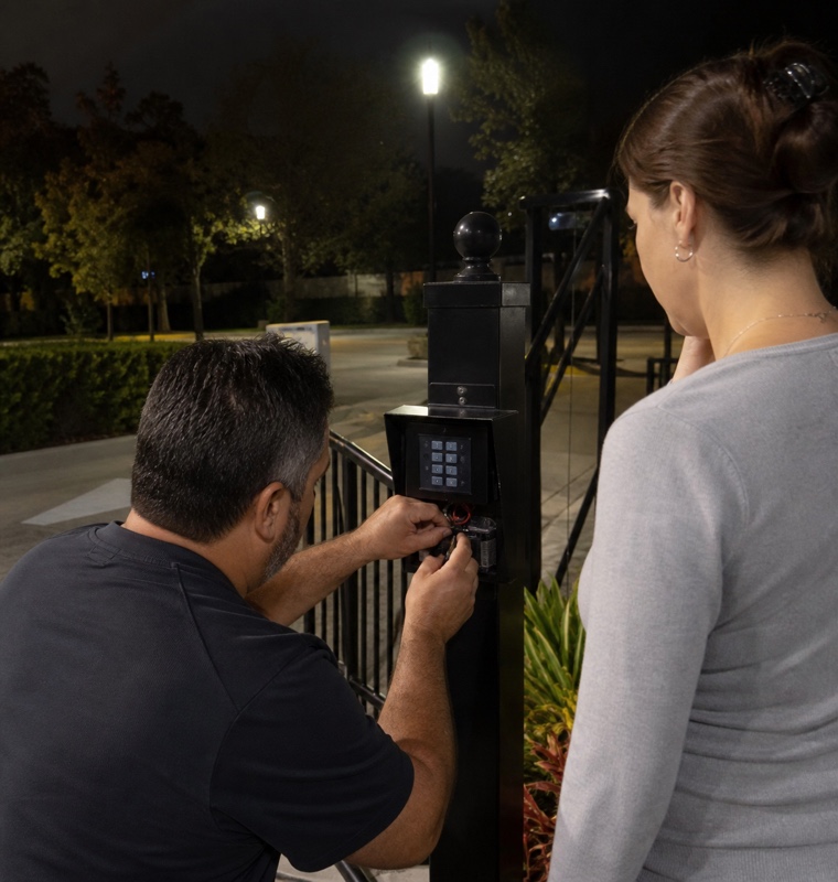Technician at a community gate keypad at night in Orlando, Florida.